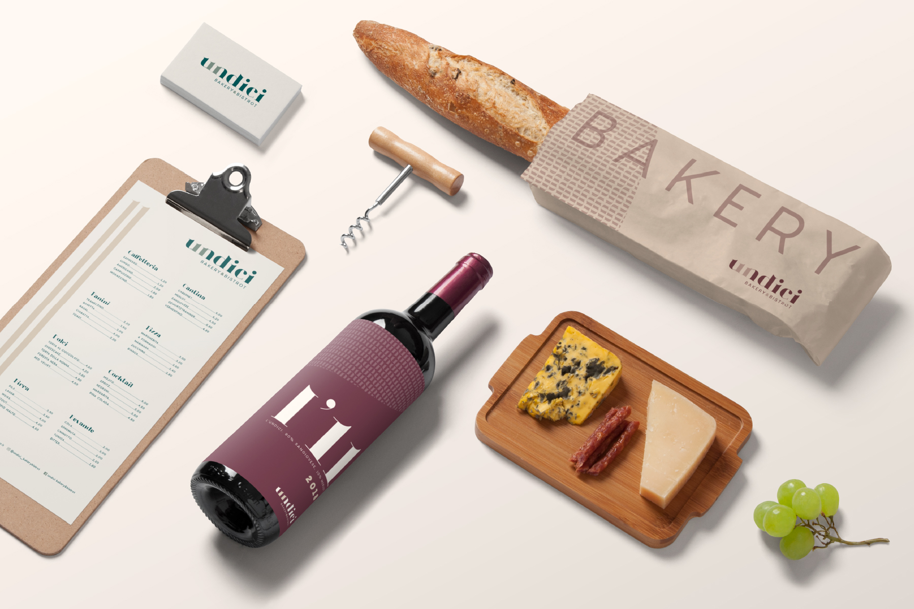 Prodotti Undici disposti su un tavolo: pane, vino, tagliere di formaggi e menu